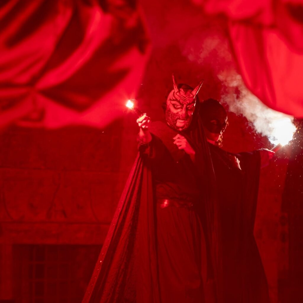 Diavolo e strega con luminosi rossi sui trampoli