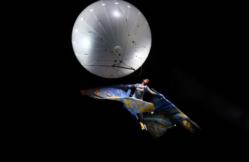 Performer from the Compagnia dei Folli suspended in mid-air by a hot-air balloon