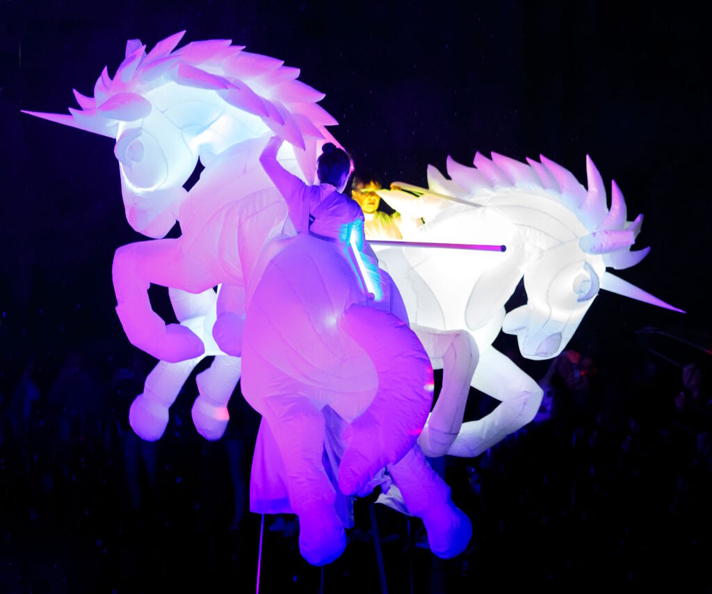 Luminous unicorns on stilts with LED lances on stilts
